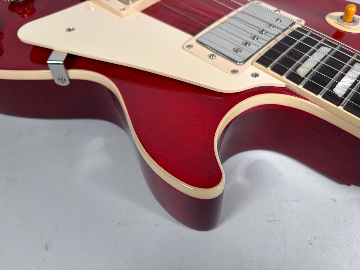 Close-up of the cherry red flame top body, showing the cream pickguard, neck pickup, and part of the bound fretboard with block inlays.