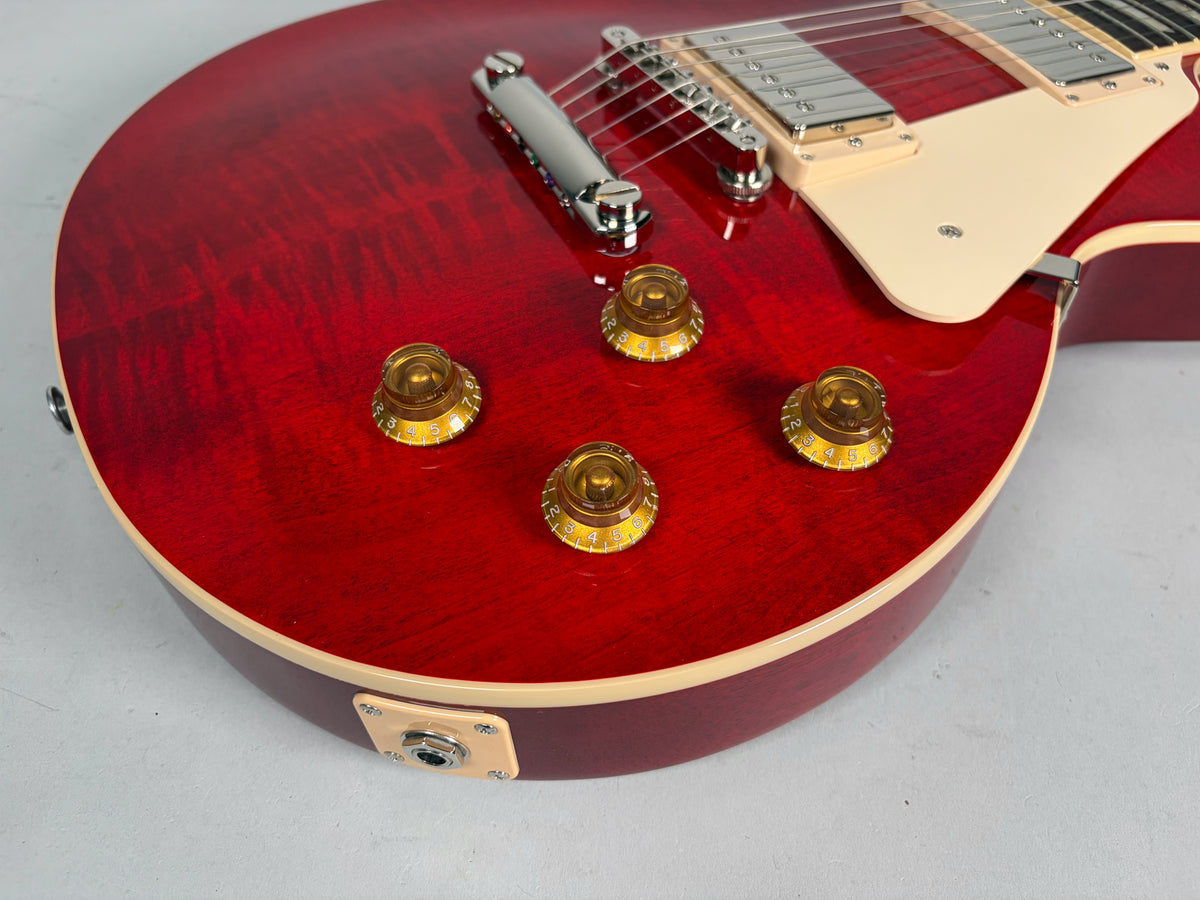 Close-up of the cherry flame top body, showing four amber top hat knobs, cream binding, and the output jack.