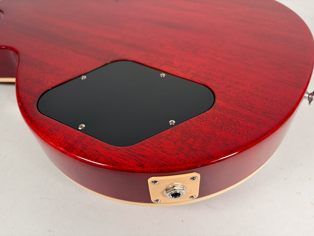 The back of the cherry red guitar shows a black control cavity cover and a cream-colored output jack plate with a chrome jack.