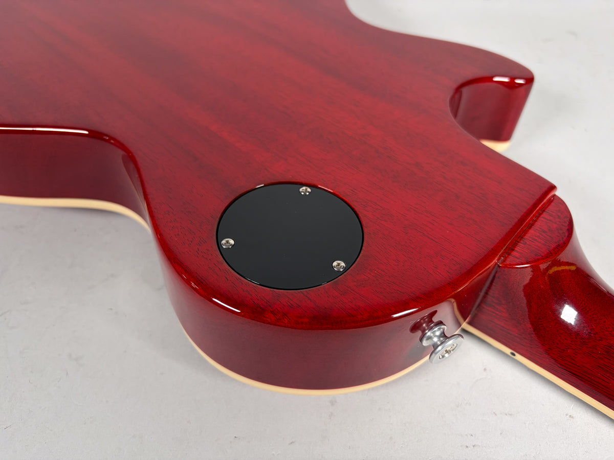 The cherry red guitar back, showing the neck joint, output jack, and a black circular control cavity cover.