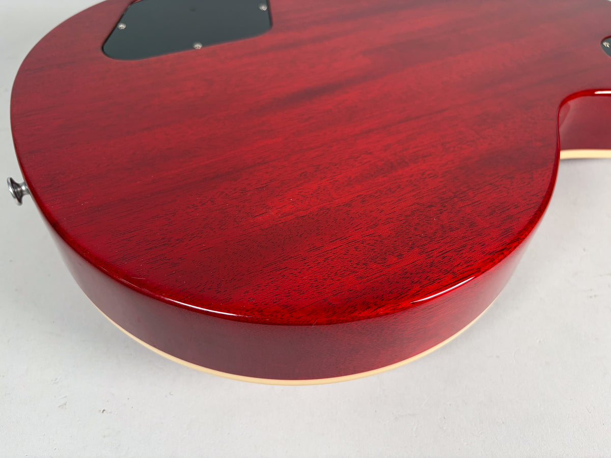 The guitar's cherry red back and side, with visible wood grain and cream binding, curves towards the bottom right.