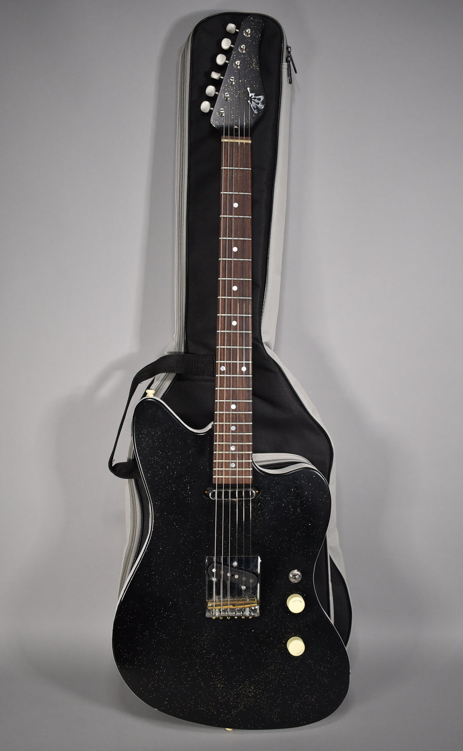 Full-length view of a black sparkle electric guitar with a single bridge pickup, two cream control knobs, and a gig bag.