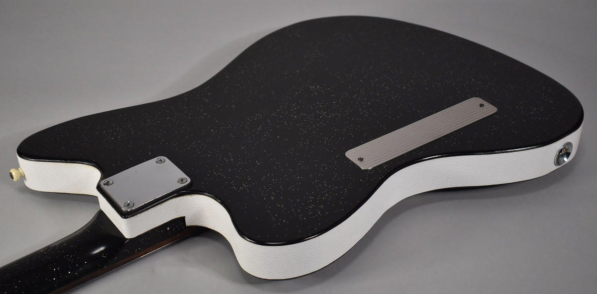 The guitar's black sparkle back and neck are visible, with white textured sides, a chrome neck plate, and a ribbed chrome tremolo cover.