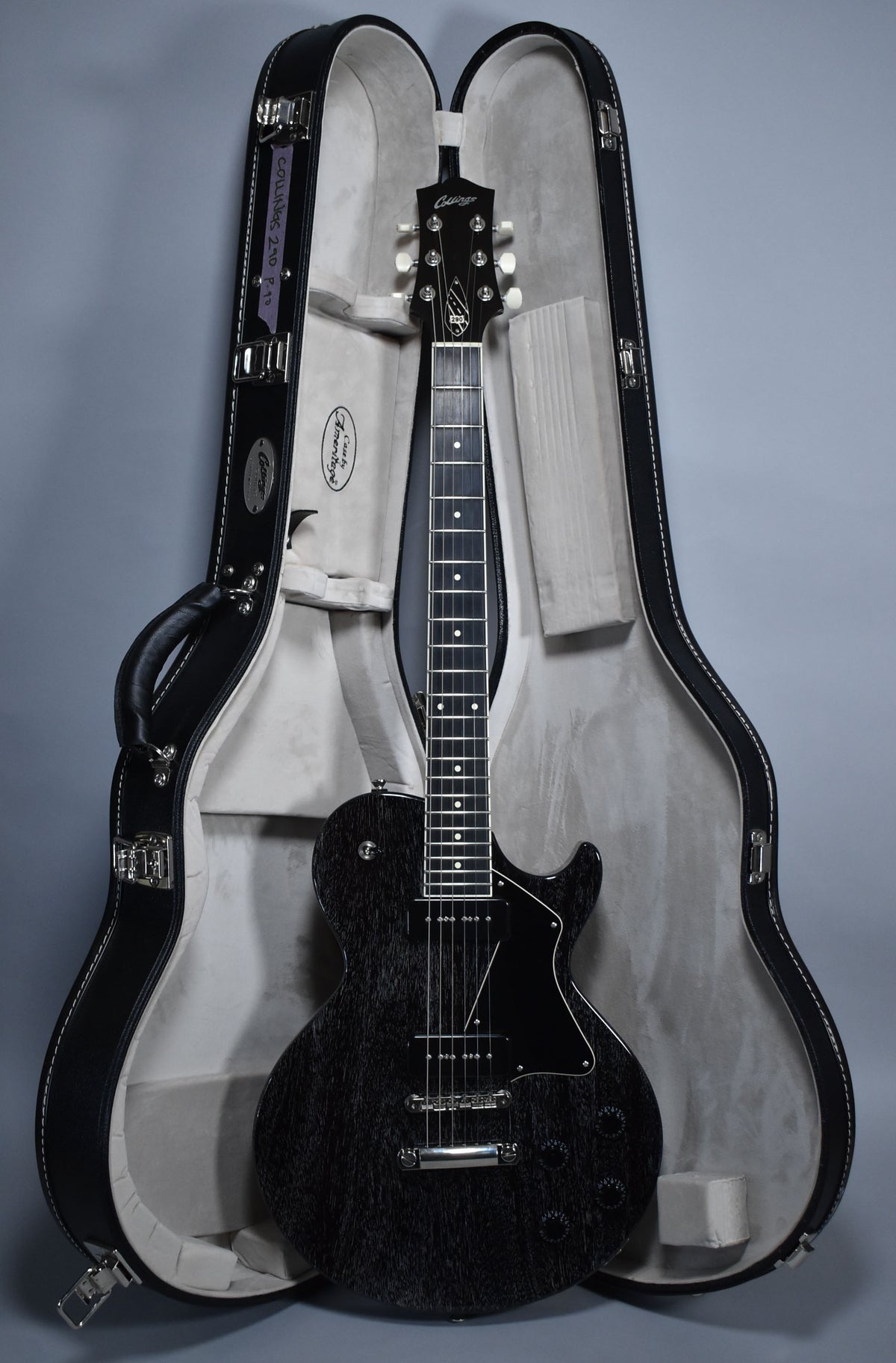 Full-length view of a black doghair-finished electric guitar with a black pickguard, chrome hardware, and white tuner buttons, in its open case.