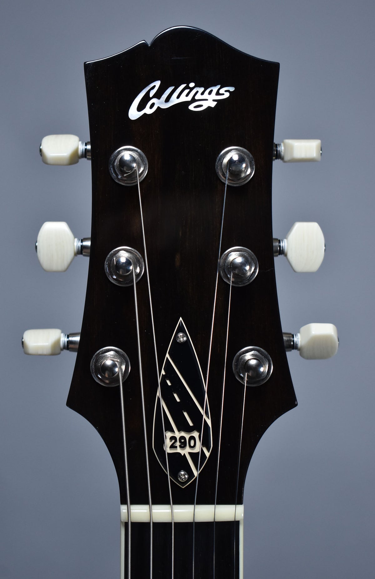 Close-up of the dark headstock with six cream tuning pegs, chrome tuners, and a white "290" highway shield inlay.