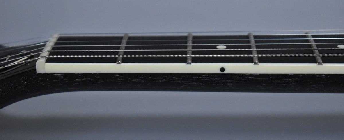 Close-up of the guitar's black fretboard and white binding, showing the first five frets and dot inlays on the fretboard and binding.