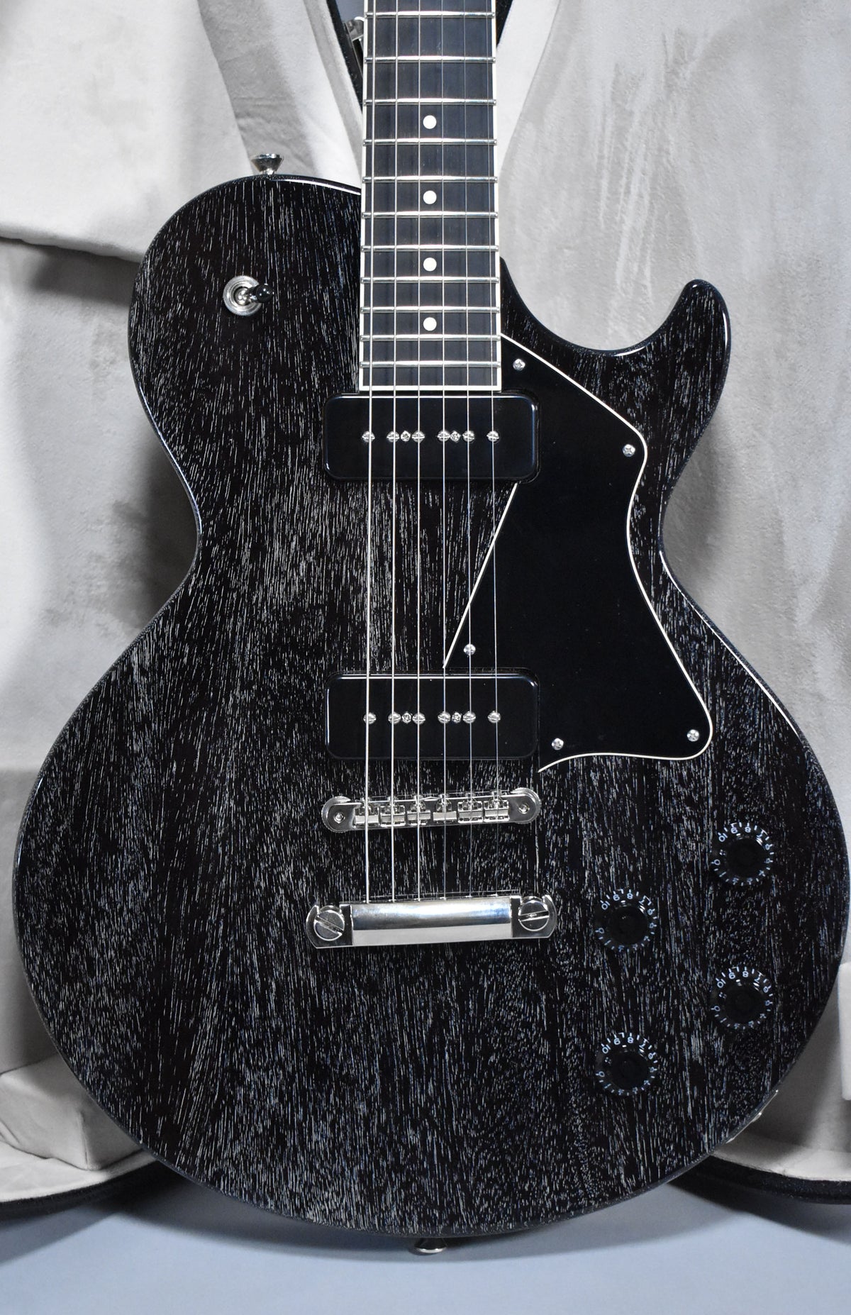 Full-frame view of the black doghair-finished electric guitar, showing two P90 pickups, a black pickguard, and four black control knobs.