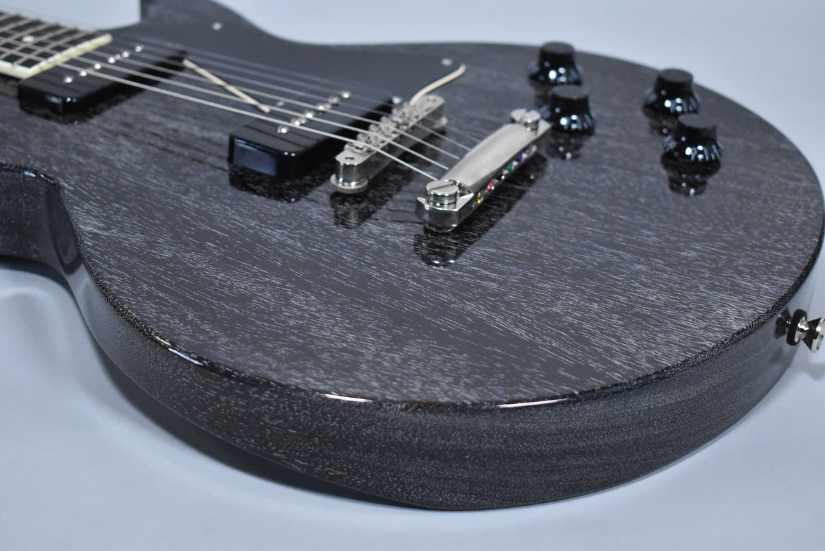 Close-up of a black doghair finish electric guitar body with two black P90 pickups, a chrome bridge, and four black control knobs.
