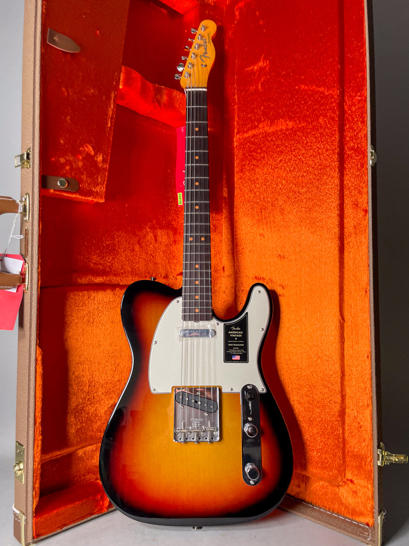 Full-body view of a sunburst Telecaster with a white pickguard, chrome bridge, and two control knobs, resting in an open orange-lined case.