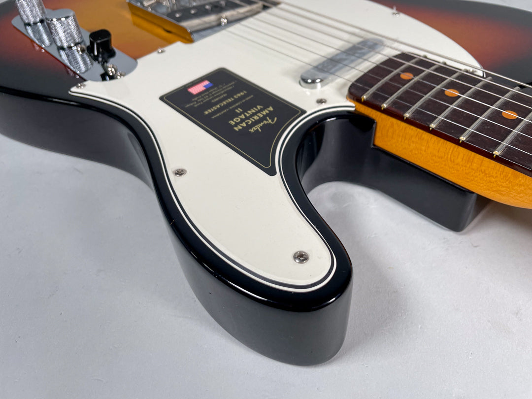 Close-up of the sunburst body and white pickguard, showing the lower horn, control plate, and part of the rosewood fretboard.