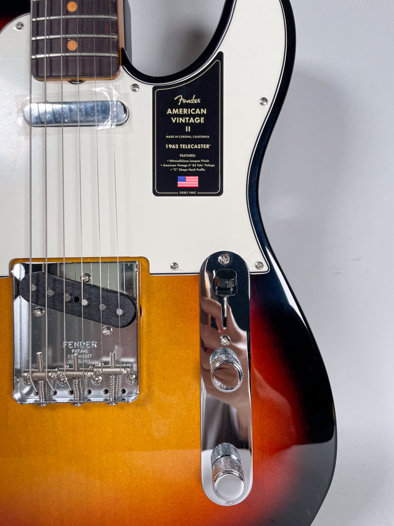 Close-up of a sunburst Telecaster body, showing the bridge pickup, chrome bridge, control plate with two knurled knobs, and a black switch tip.