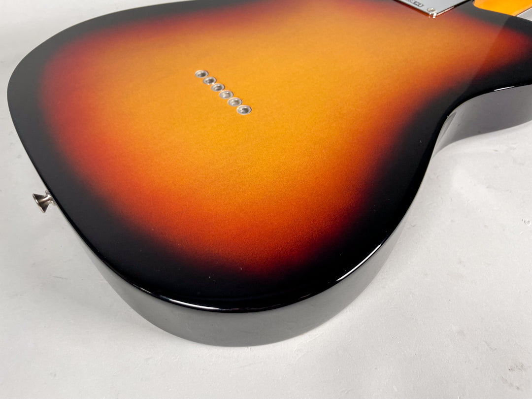 The glossy sunburst guitar body, viewed from the back, shows six string ferrules and a strap button on the lower bout.