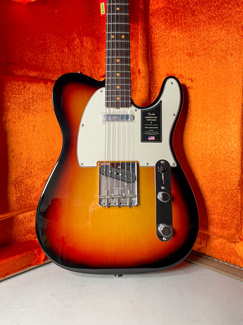 Full-body view of a sunburst Telecaster with a white pickguard, chrome bridge, and black control plate, resting in an orange plush case.
