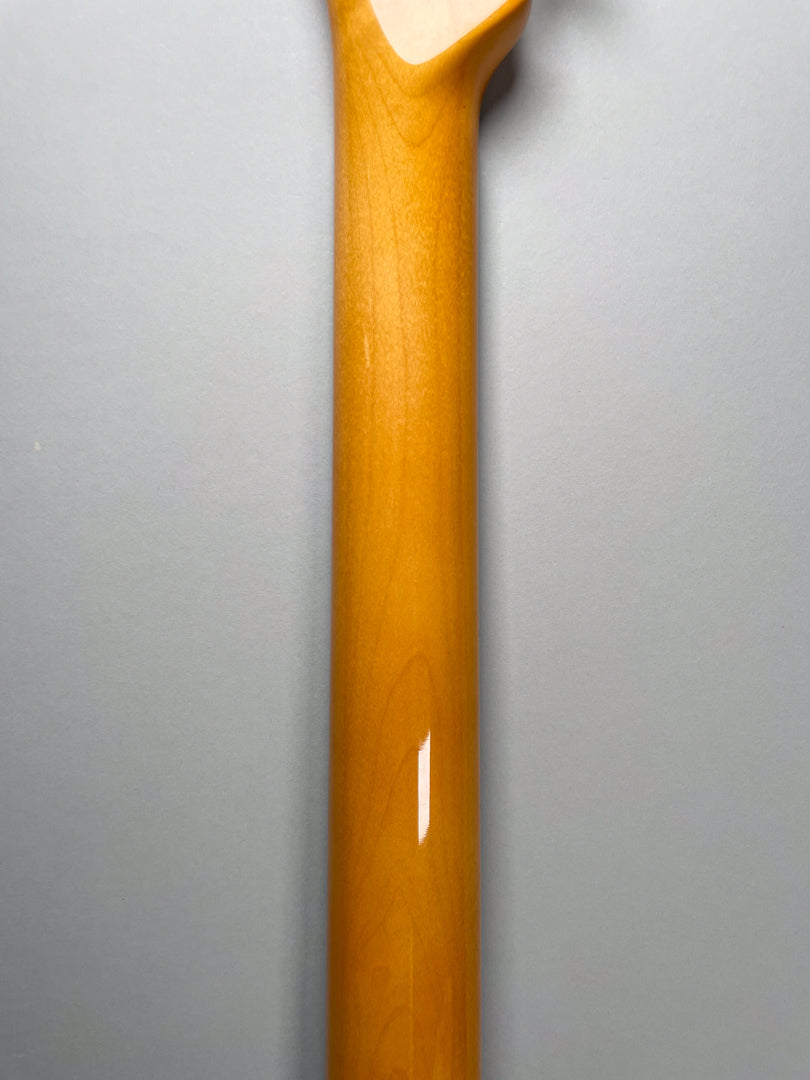 The back of the guitar's glossy amber-finished neck, with a slight reflection near the middle, against a gray background.