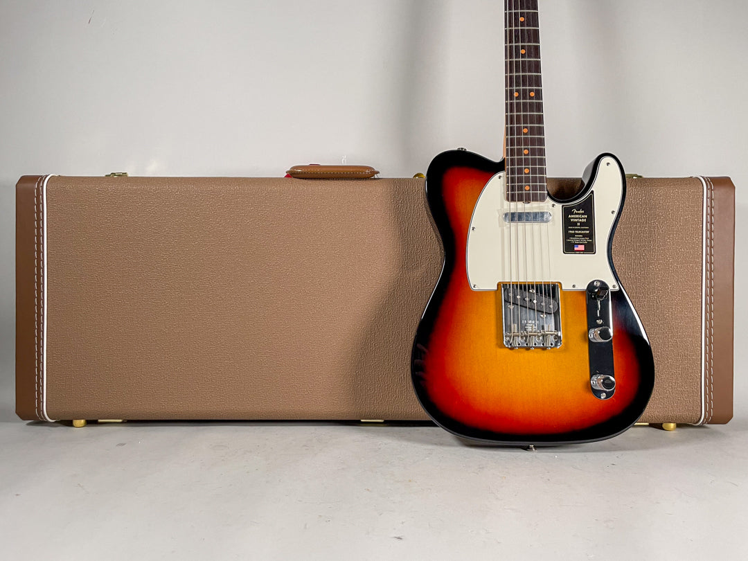Sunburst Telecaster with a white pickguard and chrome hardware, standing upright in front of a brown hardshell case.