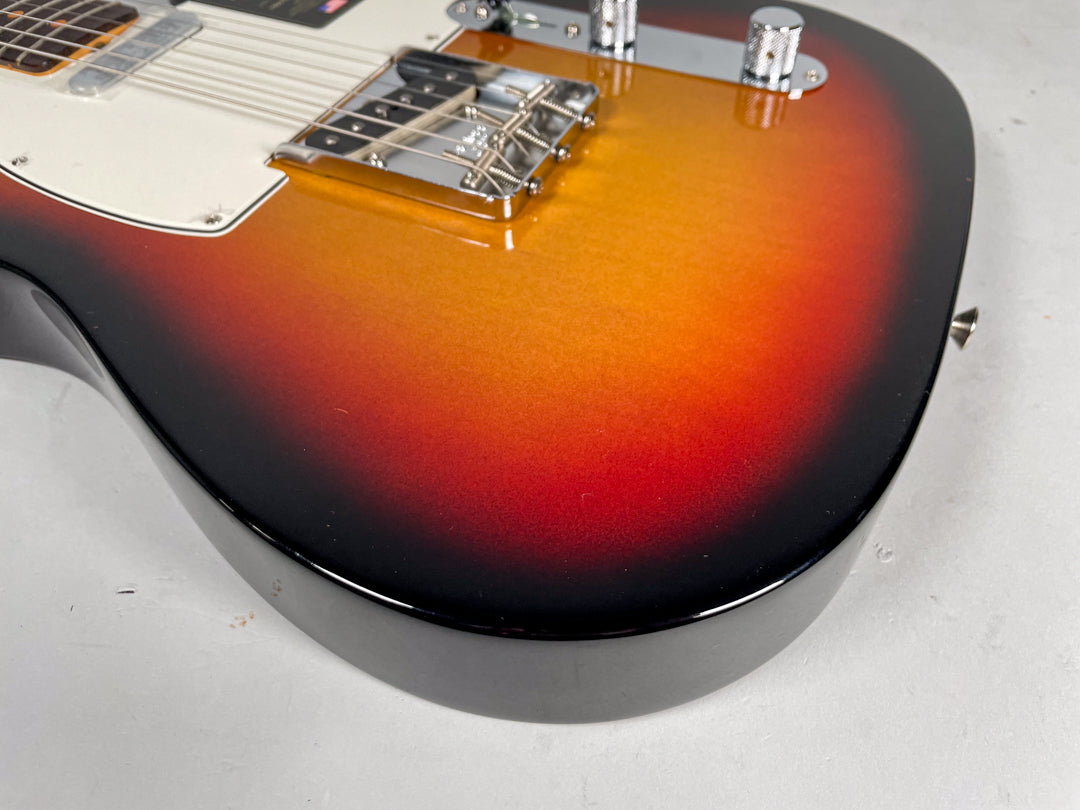 Upper bout of a sunburst Telecaster, showing the chrome bridge, control plate, and white pickguard.