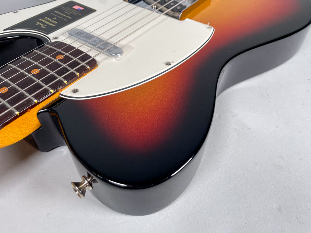 Close-up of the Telecaster's lower body, showing the sunburst finish, white pickguard, neck heel, and strap button.