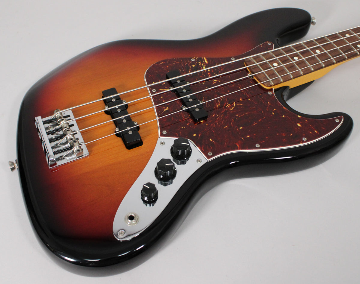 The Jazz Bass body, in 3-color sunburst with a tortoiseshell pickguard, is angled to show the chrome bridge, pickups, and control plate.