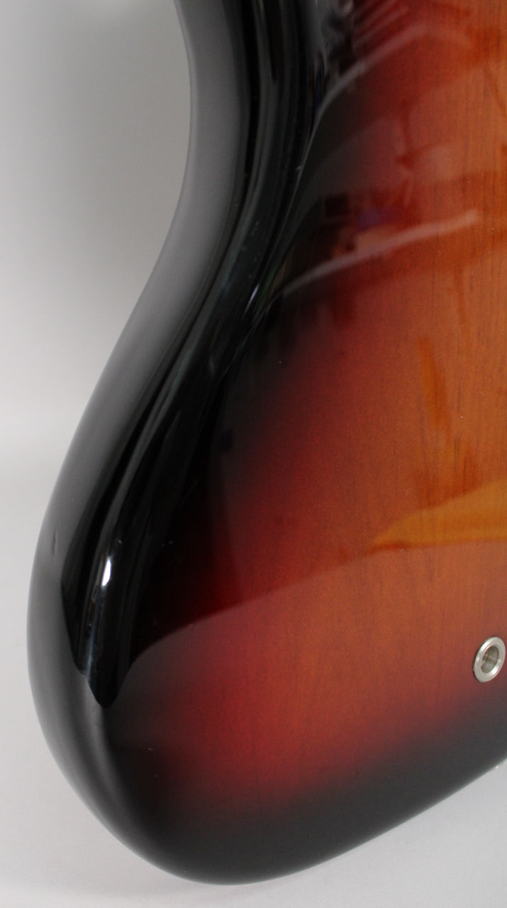 Close-up of the bass's lower bout, showing the glossy 3-color sunburst finish and a chrome strap button on the bottom edge.