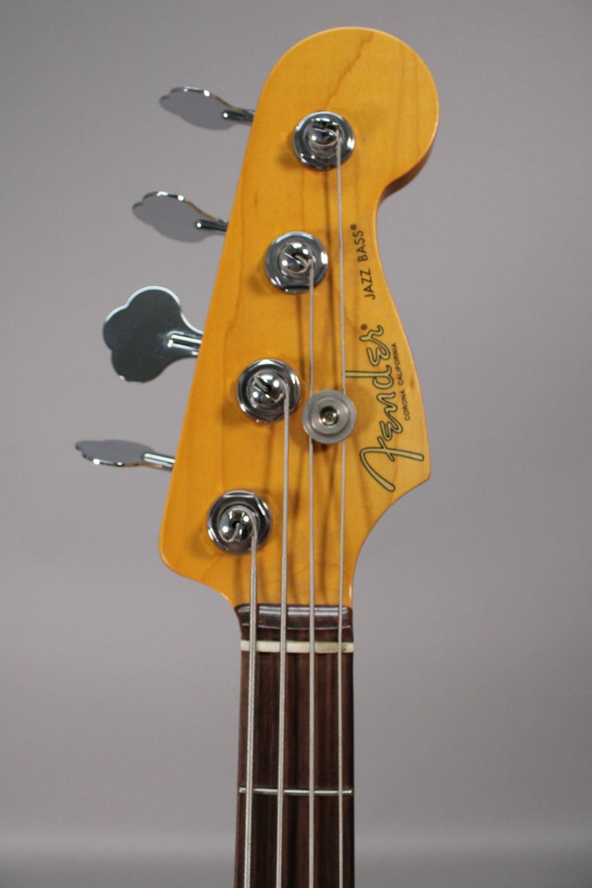 The bass headstock, with a light wood finish and four chrome tuners, is angled slightly right, showing the dark fretboard.