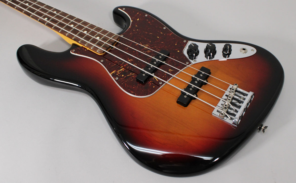 The glossy 3-color sunburst bass body, with a tortoiseshell pickguard, chrome bridge, and black control knobs, is angled from the left.