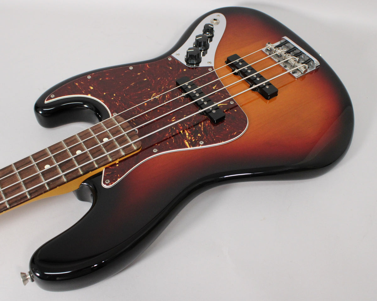 The sunburst bass guitar, with a tortoiseshell pickguard, is angled from the lower left, showing its body, pickups, and controls.