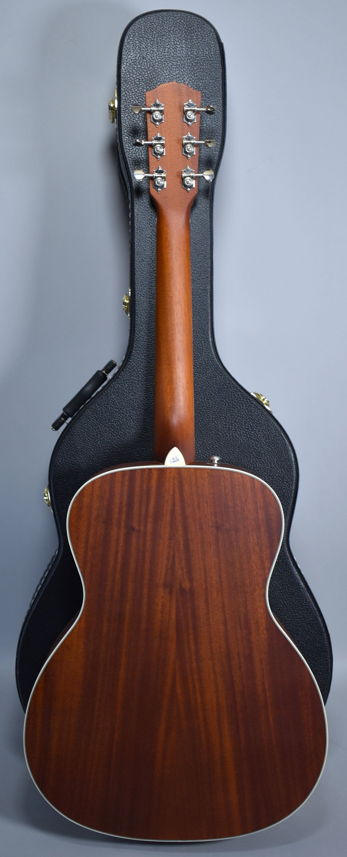 The resonator's mahogany back and neck are visible, with a black hard case behind it, showing the headstock and tuners.
