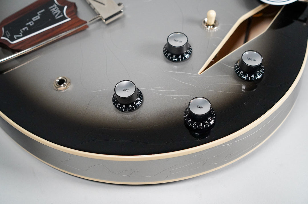 Close-up of the guitar's lower bout, showing the silverburst finish with extensive checking, four black control knobs, and a cream binding.