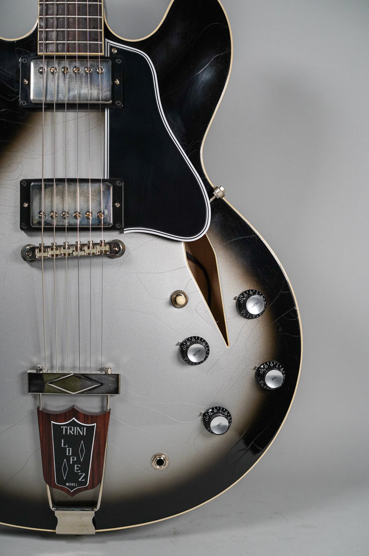 Close-up of the Silverburst body with heavy finish checking, two humbuckers, a black pickguard, and four black volume/tone knobs.
