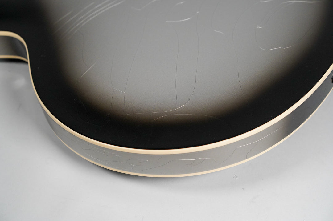 Close-up of a guitar's silverburst finish with black edges, showing light aging and finish checking on the body and side.