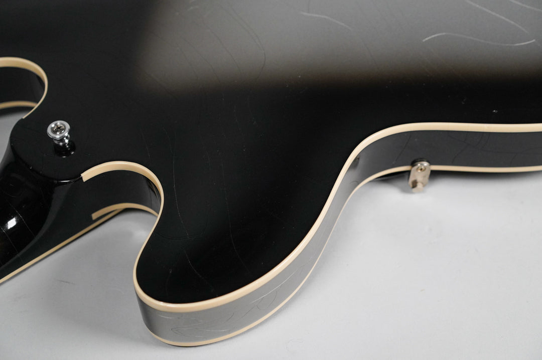 Close-up of the guitar's lower bout, showing the silverburst finish with extensive checking and cream binding, and a strap button.