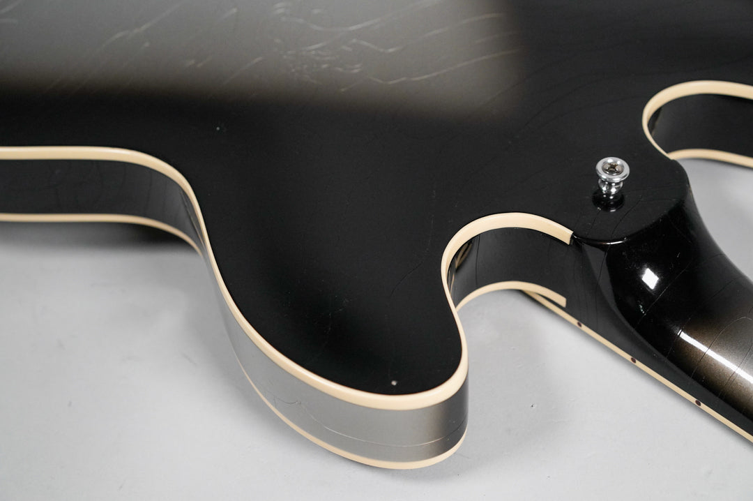 Close-up of the guitar's lower bout and neck heel, showing the Silverburst finish with light aging, binding, and strap button.