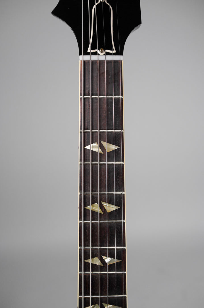 Close-up of the dark fretboard with trapezoid mother-of-pearl inlays, extending from the nut to the 12th fret.