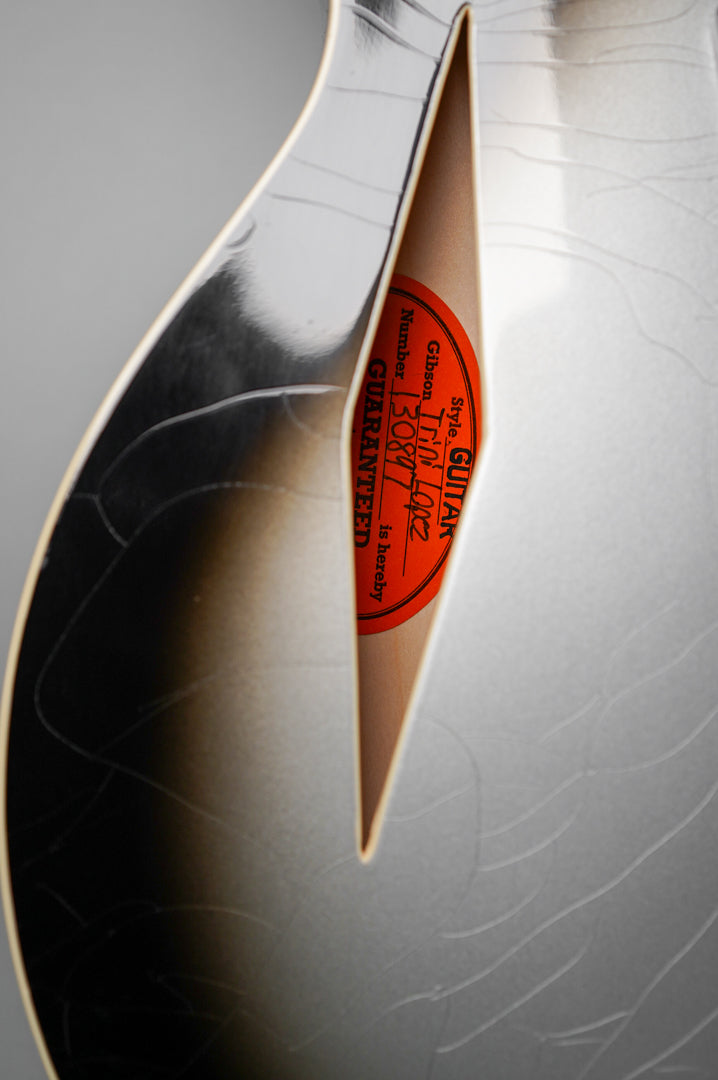 Close-up of the guitar's f-hole, revealing a red label inside and extensive finish checking on the silverburst body.
