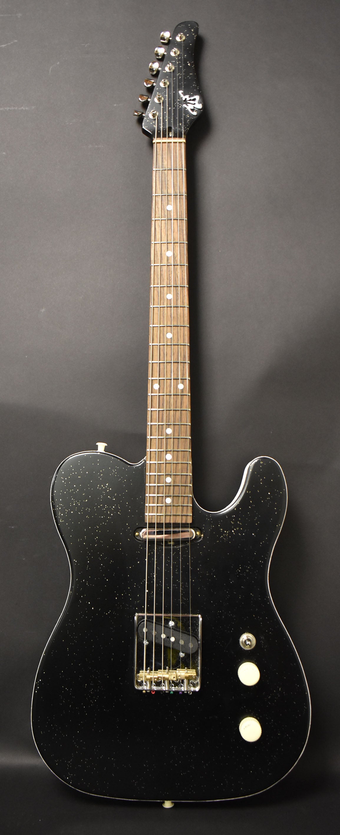 Full-length view of a black sparkle electric guitar with a light-colored fretboard, chrome tuners, and two cream control knobs.
