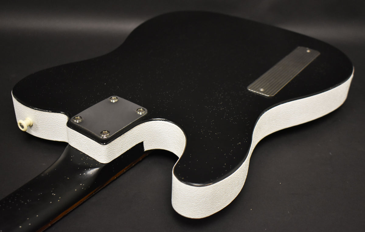 The guitar's black sparkle back and white textured sides are visible, with a chrome neck plate and string-through-body ferrule plate.