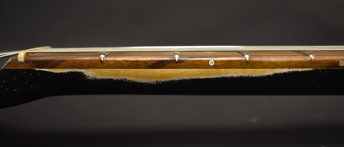 Close-up of the guitar's neck, showing heavy wear and chipping along the bottom edge of the black sparkle finish.