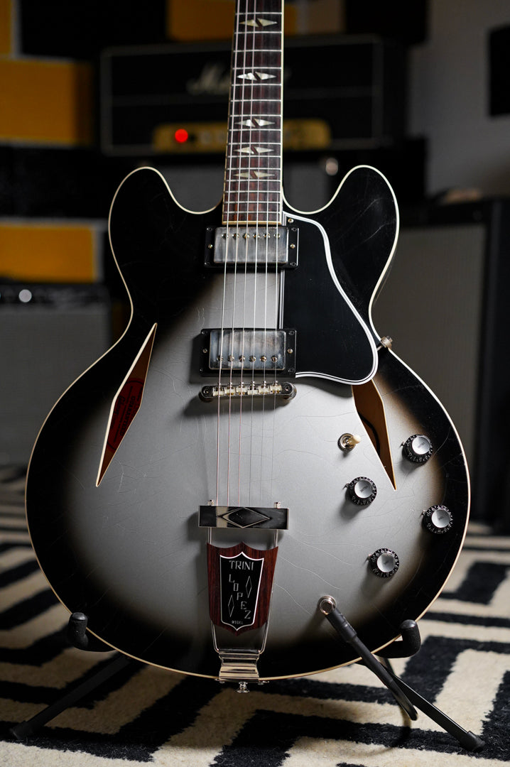 Full-frame view of a silverburst semi-hollowbody electric guitar with aged nickel hardware, visible finish checking, and a Trini Lopez tailpiece.