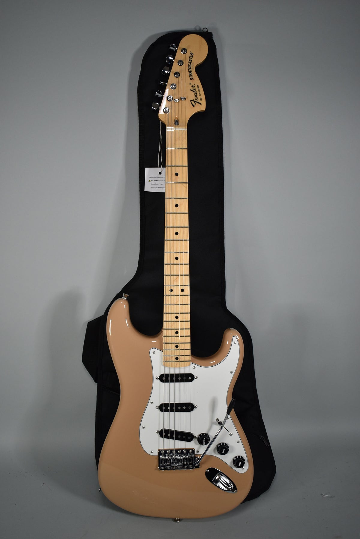 Full-length view of a Sahara Taupe Stratocaster with a maple neck, white pickguard, three black single-coil pickups, and chrome hardware.