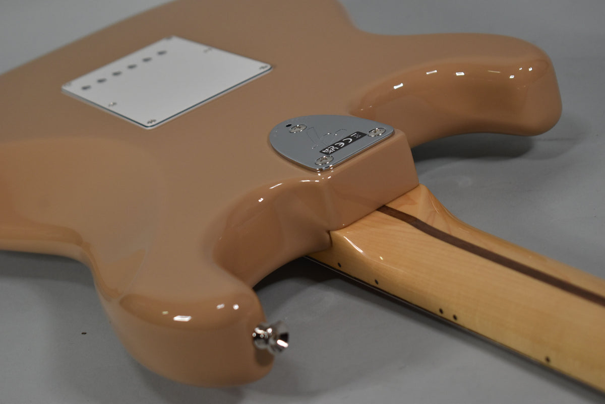 The Sahara Taupe Stratocaster's glossy back shows a white tremolo cover, chrome neck plate, and light maple neck with dark stripe.