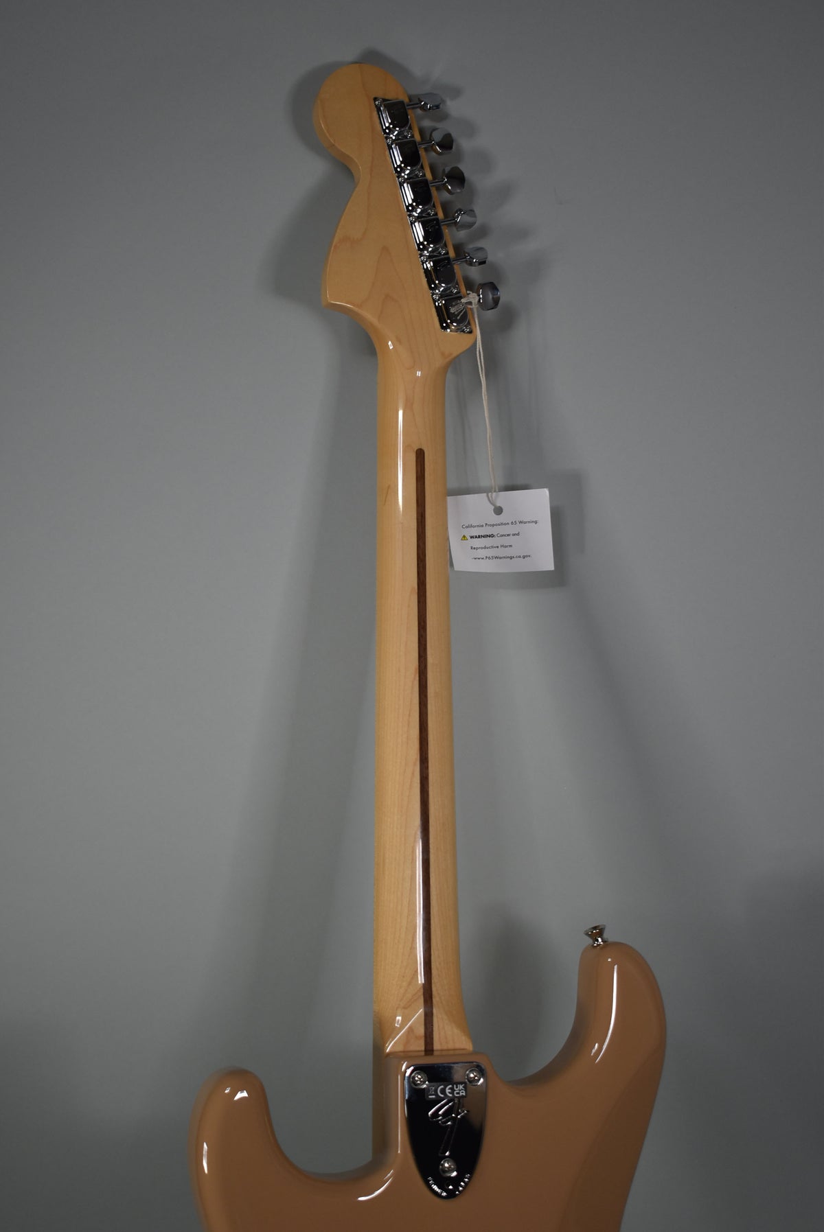 The back of a Sahara Taupe Stratocaster, showing the light maple neck, chrome tuners, and neck plate.