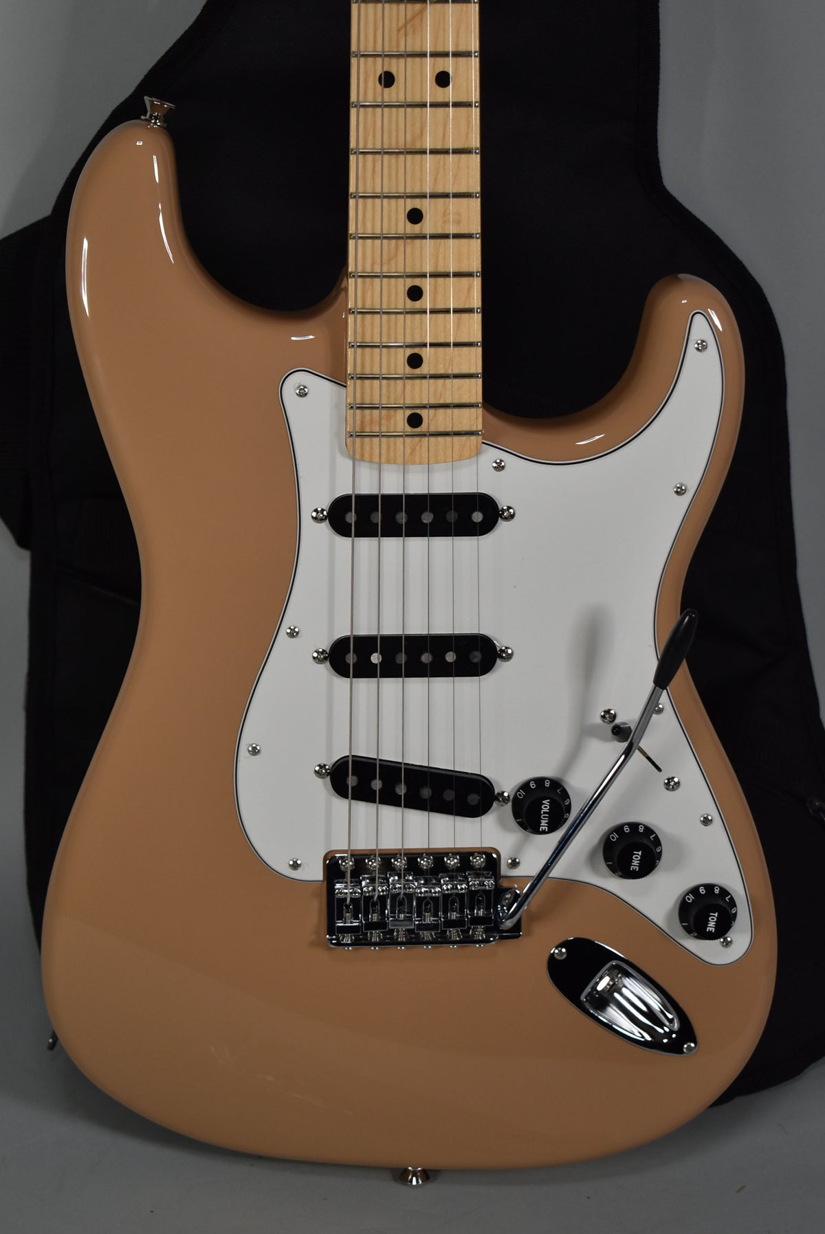 Full-frame view of a Sahara Taupe Stratocaster with a white pickguard, three black single-coil pickups, and a maple fretboard.