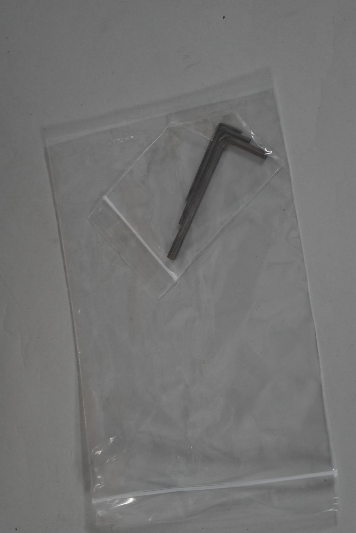 Three L-shaped hex wrenches are sealed inside a small clear plastic bag, which is inside a larger clear plastic bag.