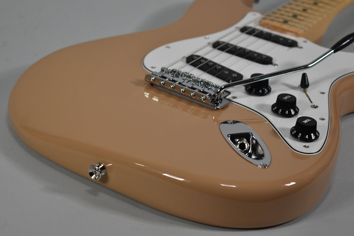 A Sahara Taupe Stratocaster body, angled from the lower bout, showing the white pickguard, three black pickups, chrome tremolo, and black control knobs.