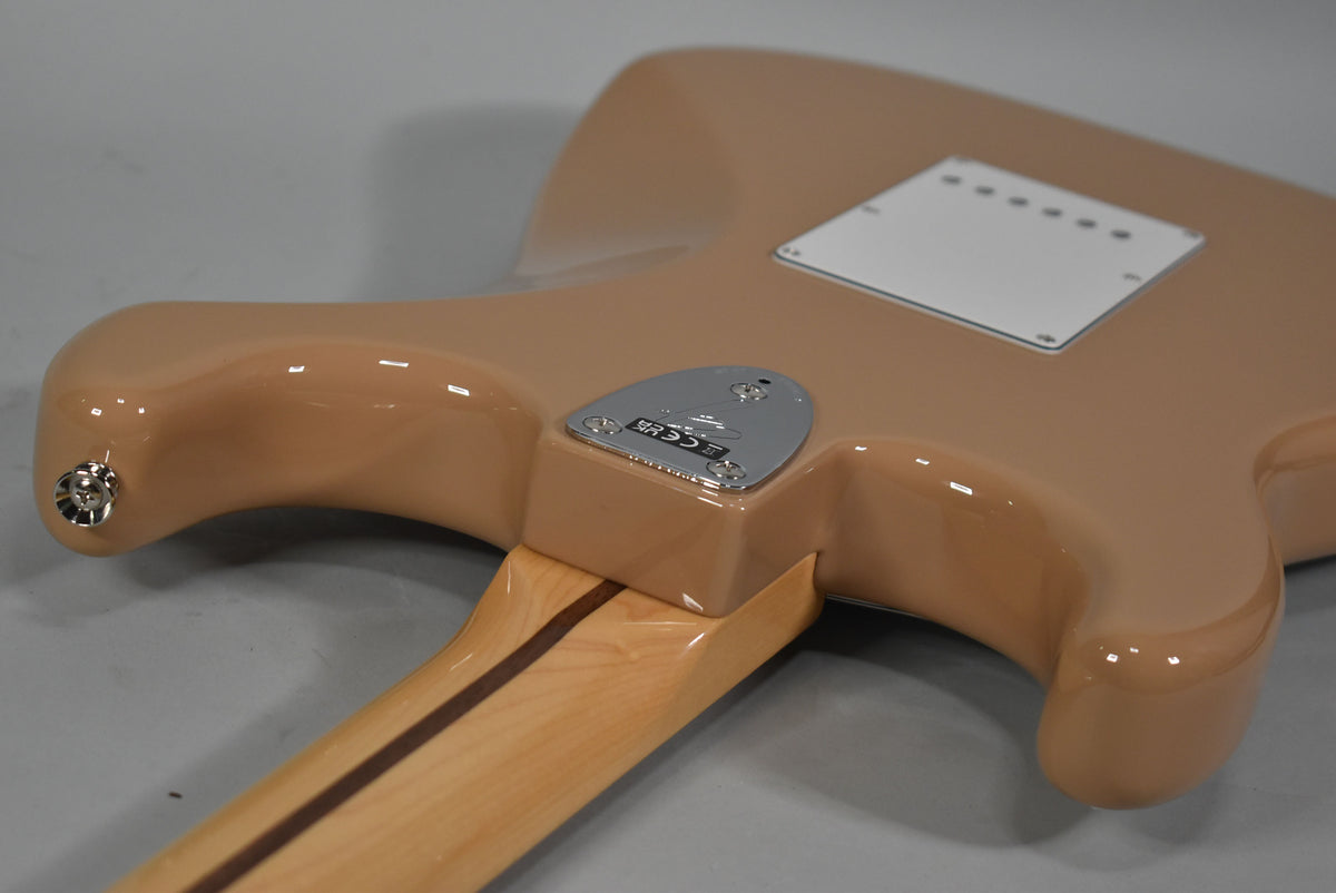 The Sahara Taupe Stratocaster's glossy back shows a chrome neck plate, white tremolo cover, and a light maple neck with dark stripe.