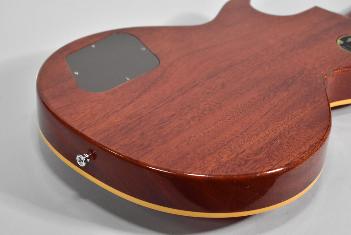The guitar's cherry red back, showing wood grain, has a black control cavity cover and a chrome strap button on the lower bout.