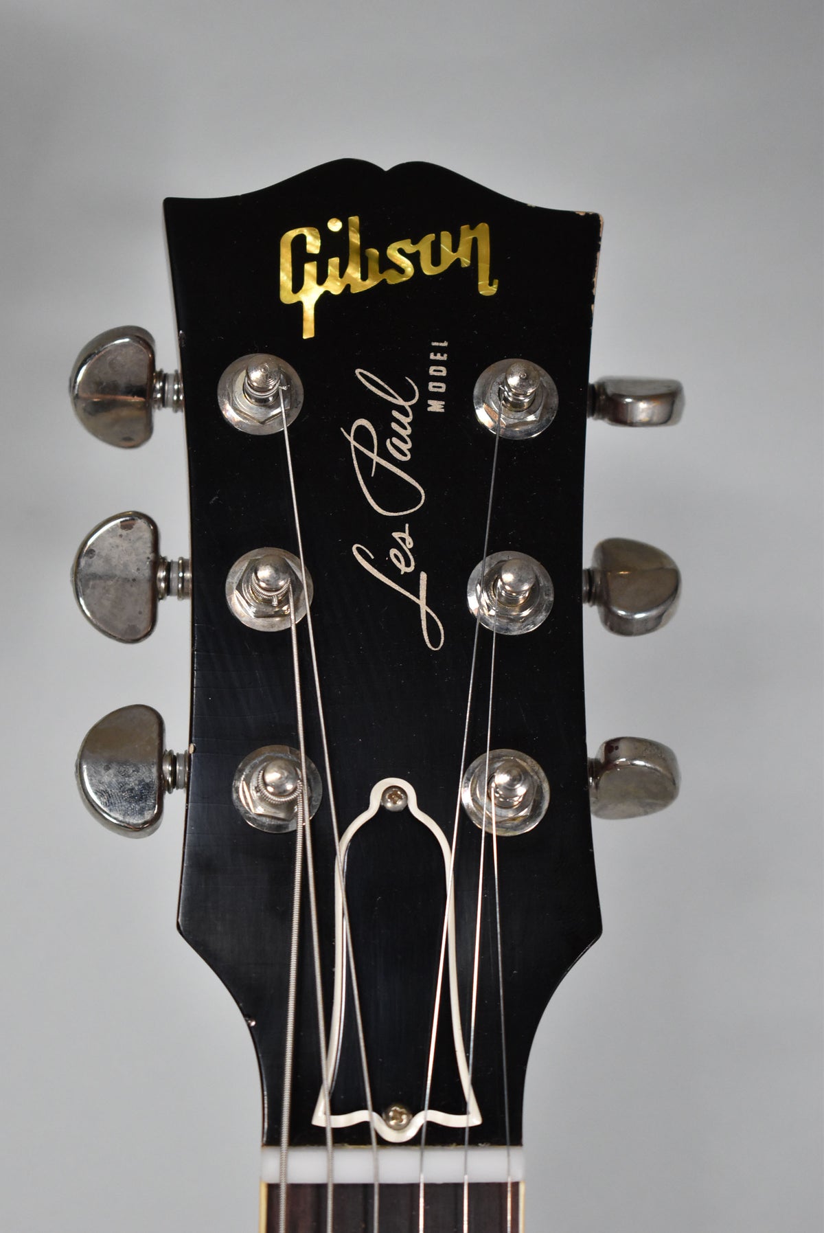 Close-up of the black headstock with gold Gibson logo, "Les Paul" script, and six aged nickel tuners with visible wear.