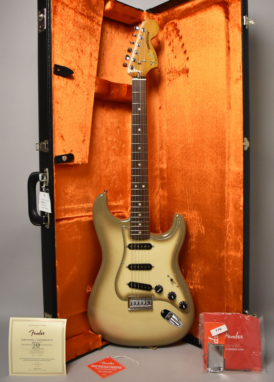 A full-length Antigua Stratocaster with a dark brown fretboard and black pickups rests in an open black case with orange plush lining.