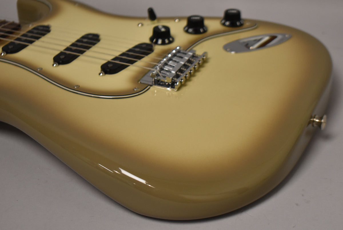 The Antigua Stratocaster's body and pickguard are visible from the lower bout, showing the chrome tremolo bridge and black controls.