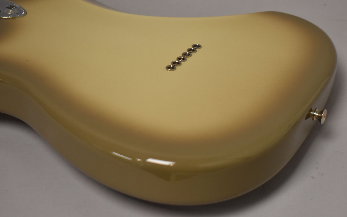 The back of a glossy Antigua Stratocaster body, showing the six string-through-body ferrules and a chrome strap button.